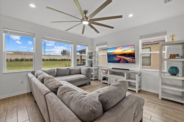 living room featuring a ceiling fan, wood finished floors, and a wealth of natural light