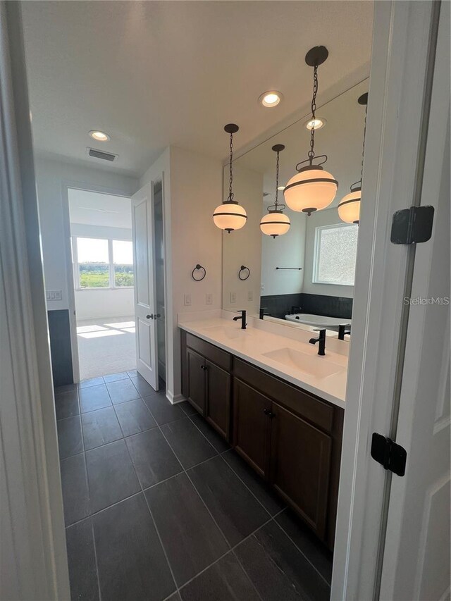 full bathroom featuring a sink, tile patterned flooring, double vanity, visible vents, and a garden tub