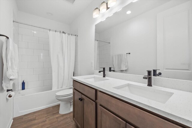 full bathroom with a sink, wood finished floors, shower / tub combo with curtain, and toilet