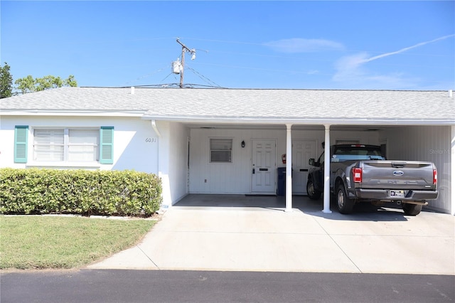 ranch-style home featuring a carport, roof with shingles, and driveway