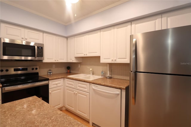 kitchen featuring light countertops, appliances with stainless steel finishes, a sink, and white cabinetry