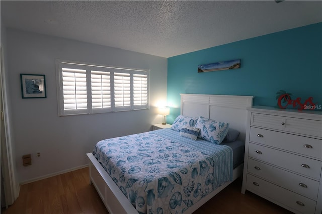 bedroom featuring a textured ceiling, baseboards, and wood finished floors