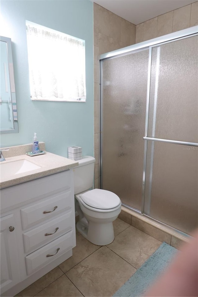 full bath featuring toilet, a stall shower, tile patterned flooring, and vanity