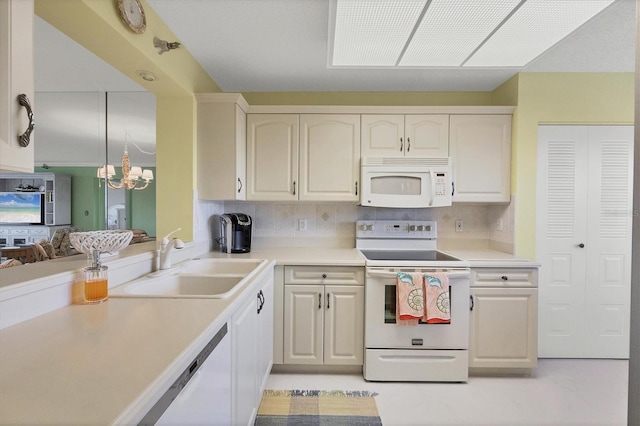 kitchen featuring white appliances, a sink, an inviting chandelier, light countertops, and backsplash