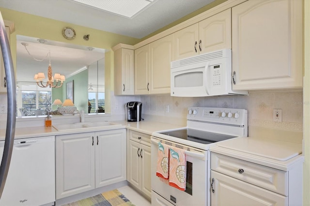 kitchen featuring white appliances, a sink, decorative backsplash, and an inviting chandelier