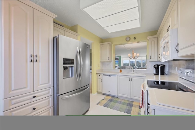 kitchen with light countertops, decorative backsplash, a sink, a chandelier, and white appliances