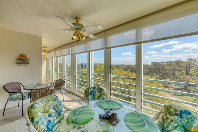 sunroom / solarium featuring a view of city and a ceiling fan