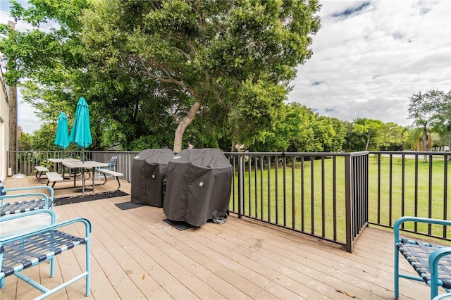 wooden deck with outdoor dining space, a lawn, and grilling area