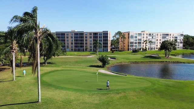 view of home's community featuring view of golf course, a lawn, and a water view