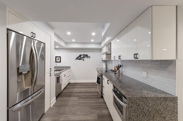 kitchen with white cabinetry, appliances with stainless steel finishes, decorative backsplash, and dark wood-type flooring