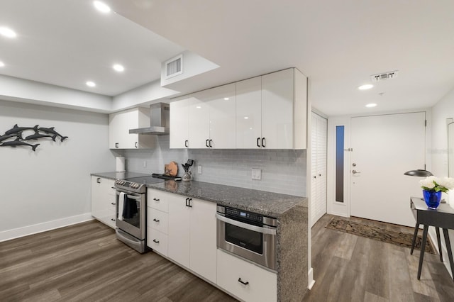 kitchen featuring wall chimney exhaust hood, visible vents, stainless steel appliances, and dark wood finished floors