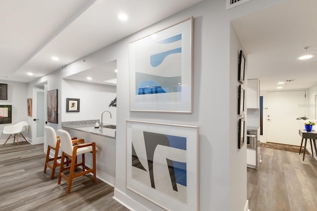 interior space with a sink, baseboards, wood finished floors, and recessed lighting