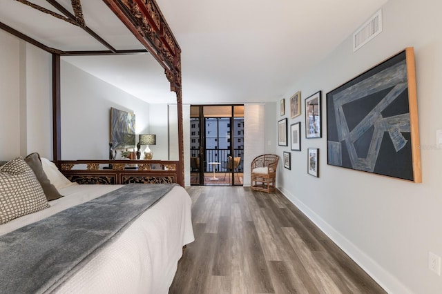 bedroom with dark wood-style floors, visible vents, expansive windows, access to outside, and baseboards