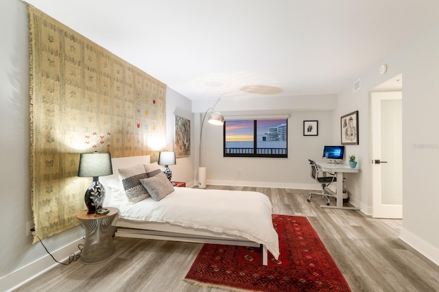 bedroom with visible vents, baseboards, and wood finished floors