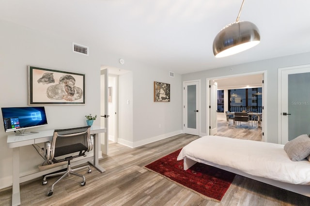 bedroom featuring french doors, wood finished floors, visible vents, and baseboards