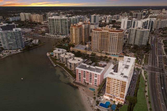 aerial view at dusk featuring a view of city and a water view