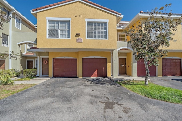 view of front of home featuring an attached garage, driveway, a tiled roof, and stucco siding