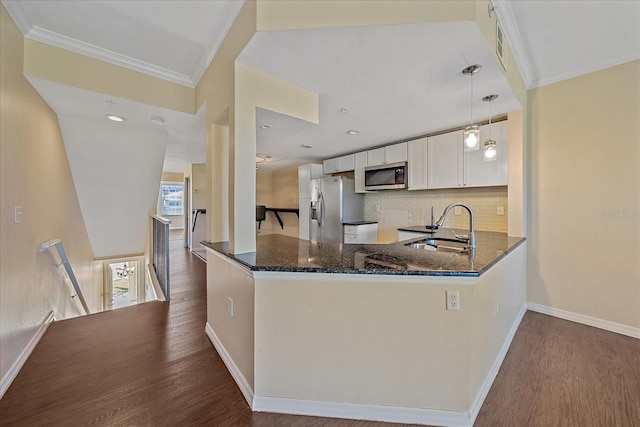 kitchen featuring a peninsula, dark wood-type flooring, a sink, appliances with stainless steel finishes, and dark stone counters