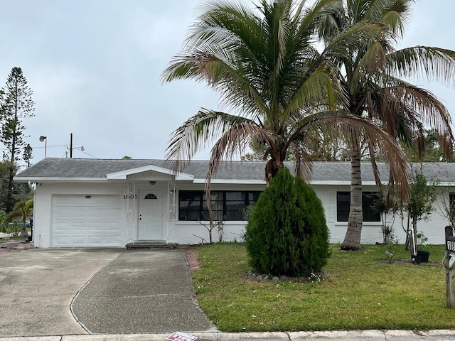 ranch-style house with driveway, stucco siding, an attached garage, and a front yard