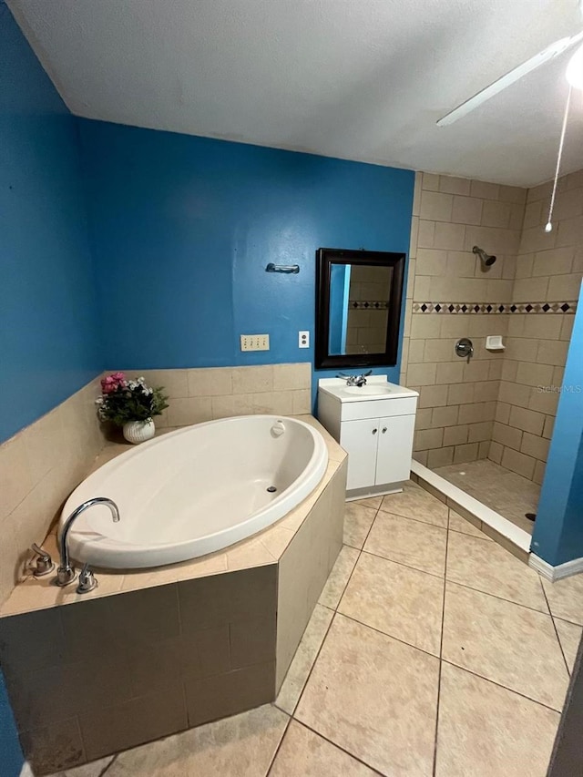 full bath featuring tile patterned floors, a tile shower, a bath, and vanity