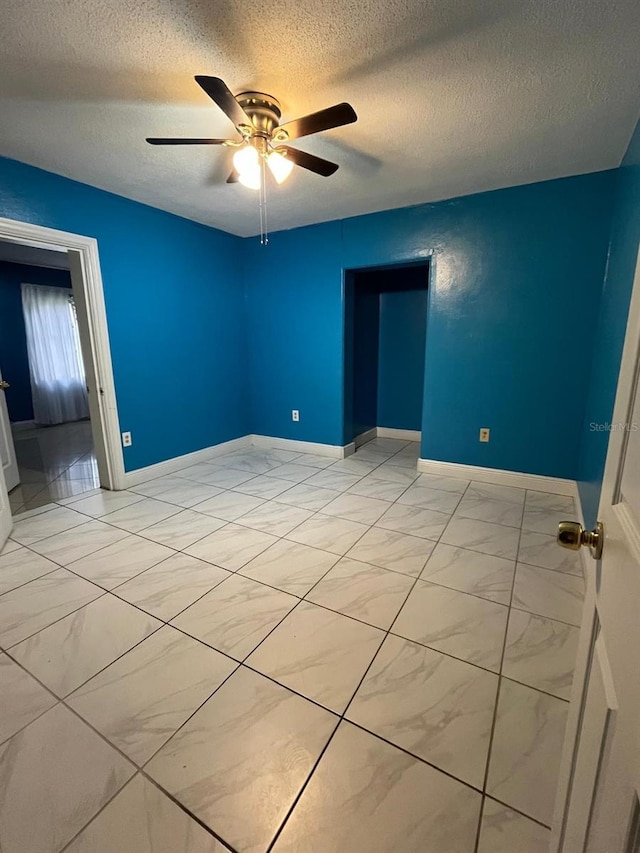 empty room featuring a textured ceiling, baseboards, and a ceiling fan