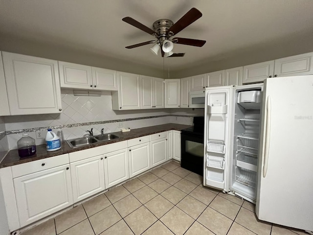 kitchen with tasteful backsplash, dark countertops, white cabinetry, a sink, and white appliances