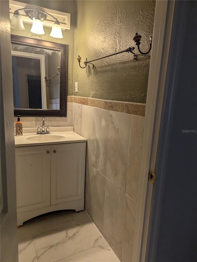 1807 48th Ave W, Bradenton, FL 34207 - bathroom with vanity, marble look tile flooring, tile walls, wainscoting, and a textured wall