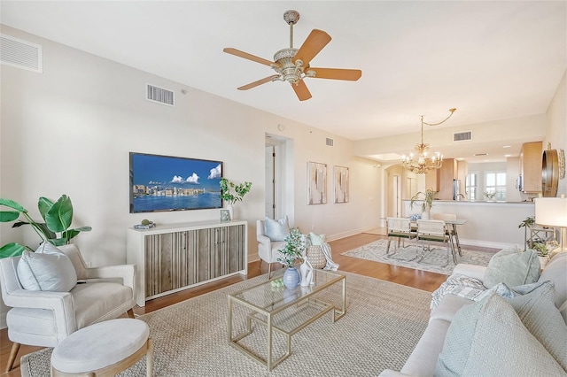 living area with baseboards, visible vents, wood finished floors, and ceiling fan with notable chandelier