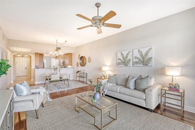 living area with ceiling fan with notable chandelier, wood finished floors, and baseboards