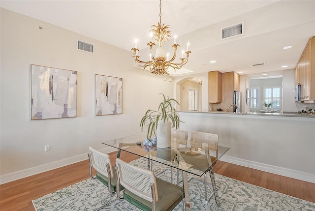 dining space featuring arched walkways, wood finished floors, visible vents, and baseboards