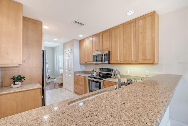 kitchen with light stone countertops, stainless steel appliances, and recessed lighting