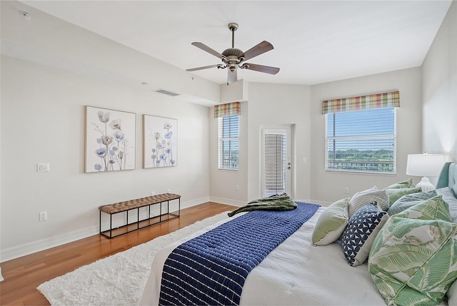 bedroom with access to exterior, wood finished floors, visible vents, and baseboards