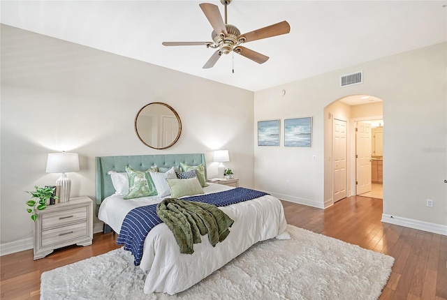 bedroom with visible vents, arched walkways, baseboards, hardwood / wood-style flooring, and ceiling fan