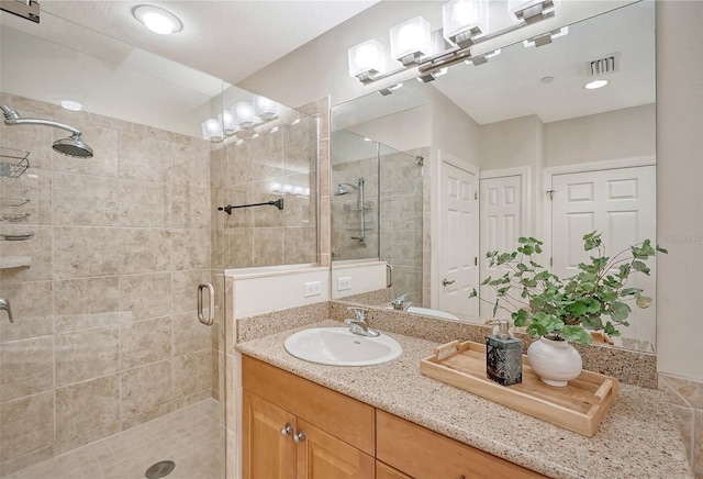 full bathroom featuring a shower stall, visible vents, and vanity