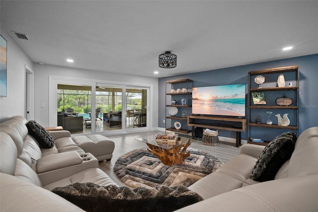 living room with recessed lighting, visible vents, and wood finished floors