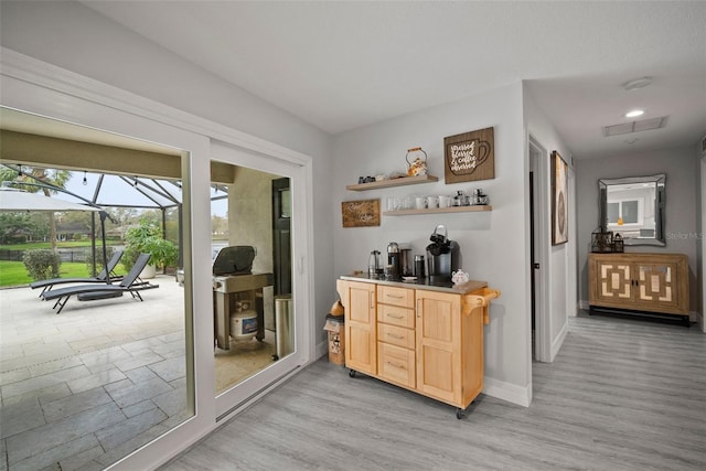 bar with indoor wet bar, light wood finished floors, baseboards, and a sunroom