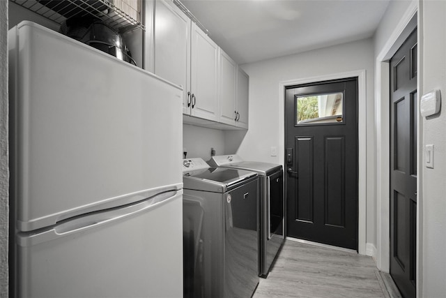 laundry area with washing machine and clothes dryer, cabinet space, and light wood-style floors