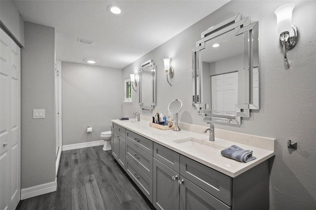 bathroom featuring visible vents, toilet, a sink, wood finished floors, and baseboards