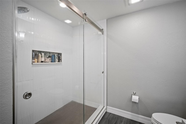 full bath featuring a stall shower, toilet, baseboards, and a textured wall