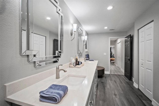 ensuite bathroom with a sink, a closet, and wood finished floors