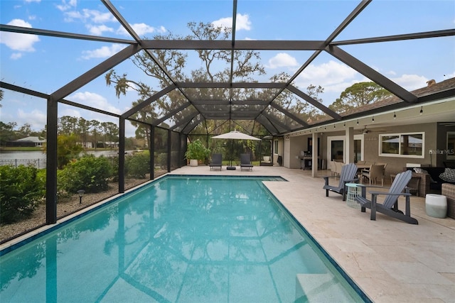 outdoor pool featuring glass enclosure, a ceiling fan, and a patio