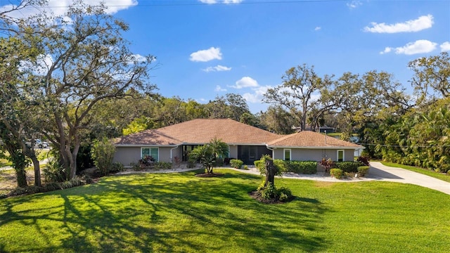 ranch-style house with stucco siding, concrete driveway, and a front yard