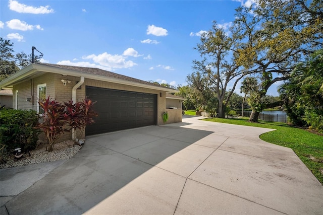 view of home's exterior with brick siding, driveway, a garage, and fence