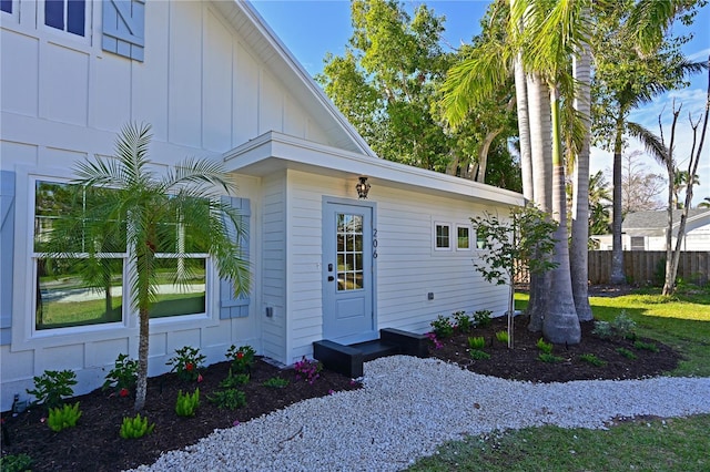 property entrance with fence and board and batten siding