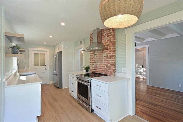 kitchen featuring wall chimney exhaust hood, light wood-style flooring, appliances with stainless steel finishes, open shelves, and a sink