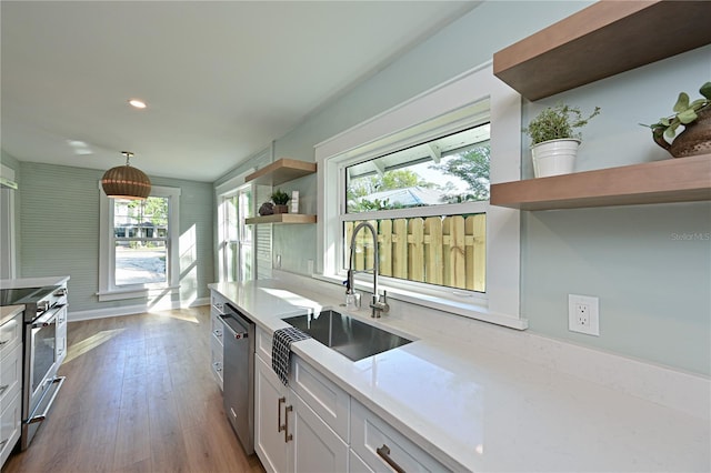 kitchen featuring dark wood finished floors, open shelves, appliances with stainless steel finishes, white cabinets, and a sink