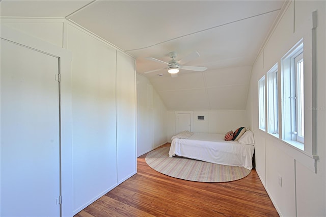 unfurnished bedroom with ceiling fan, visible vents, vaulted ceiling, and wood finished floors