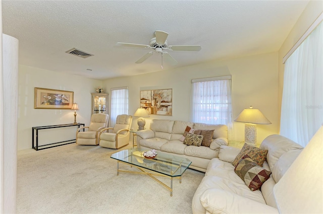 carpeted living area with ceiling fan, visible vents, and a textured ceiling