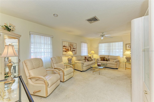 carpeted living area featuring ceiling fan, visible vents, and a textured ceiling