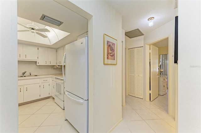 kitchen featuring light tile patterned floors, visible vents, range, freestanding refrigerator, and a sink